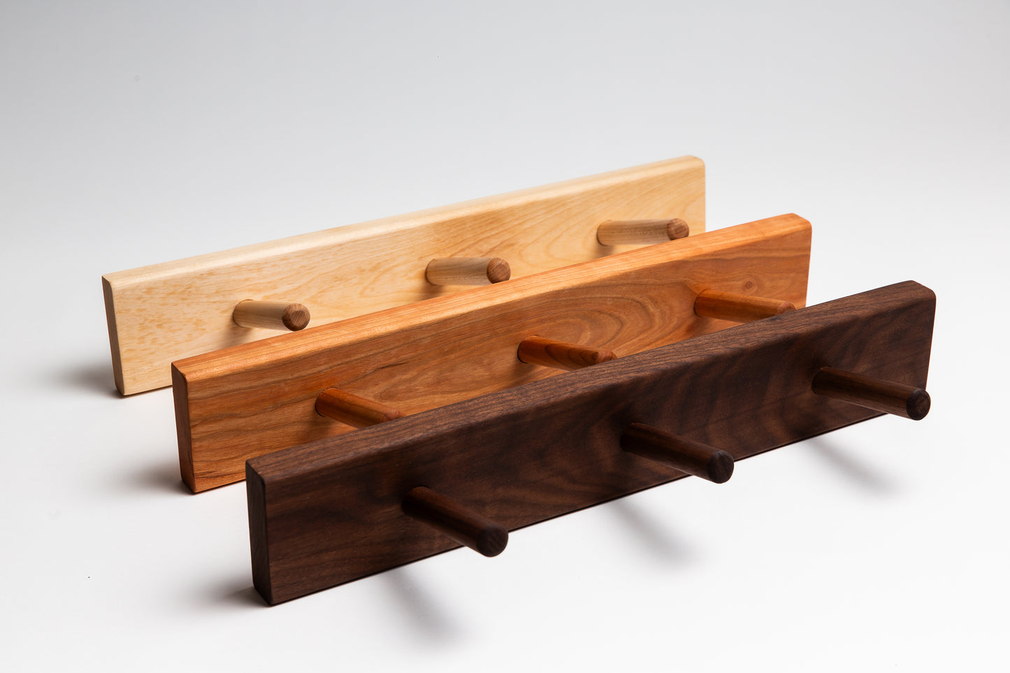 3 peg wooden dowel racks showing the three colours available. The coat racks come in birch, cherry, and walnut.