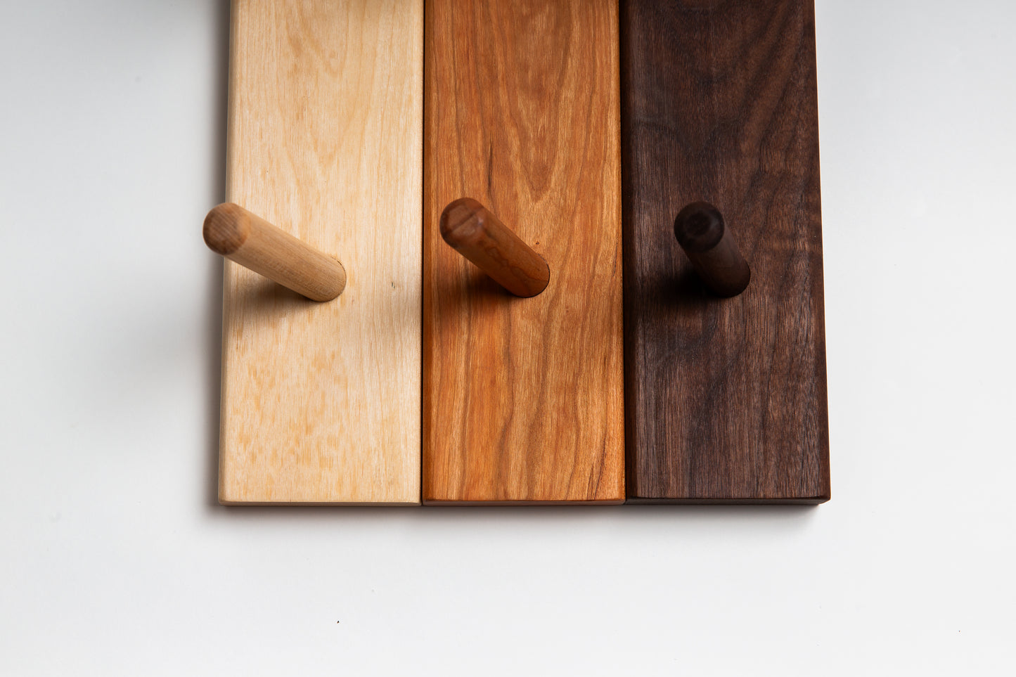 Close-up shot of wooden coat racks in three kinds of wood: birch, cherry, and walnut.