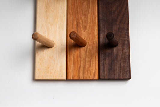 Close-up shot of wooden coat racks in three kinds of wood: birch, cherry, and walnut.