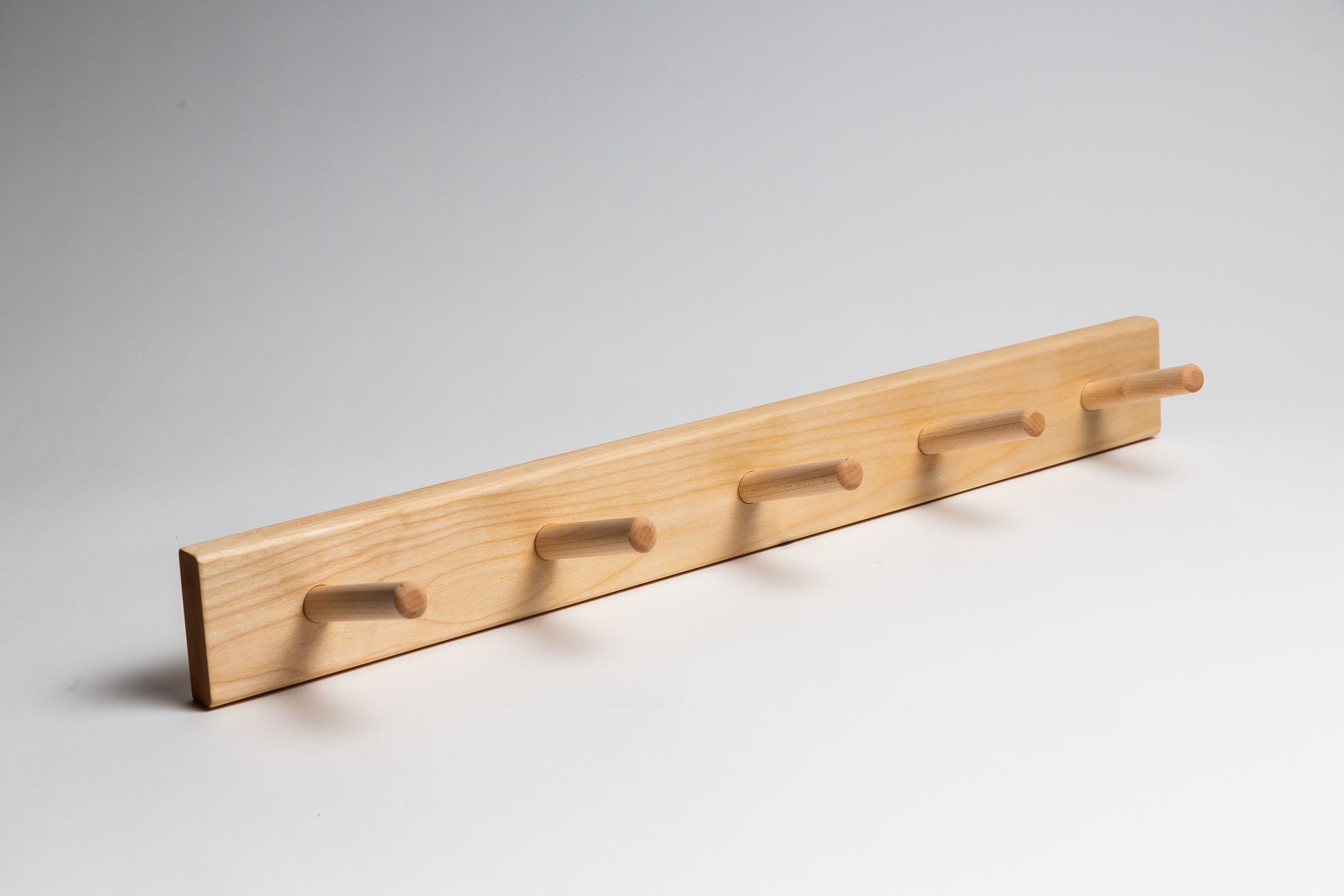 A 5 dowel wall coat rack made from birch wood.